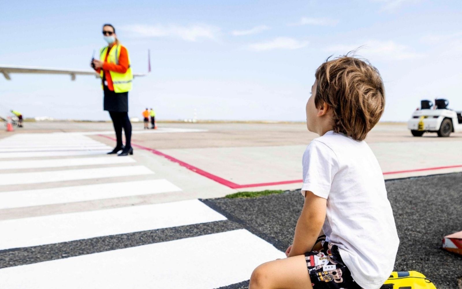 A young passenger sits on a Trunki suitcase on the tarmac at Avalon, Melbourne airport's curfew-free international gateway, as ground crew prepare for departure