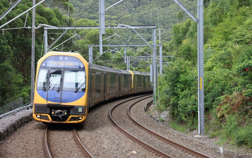 A Sydney Trains service rounds a curve through bushland on a corridor affected by the Sydney to Melbourne train shutdown in May