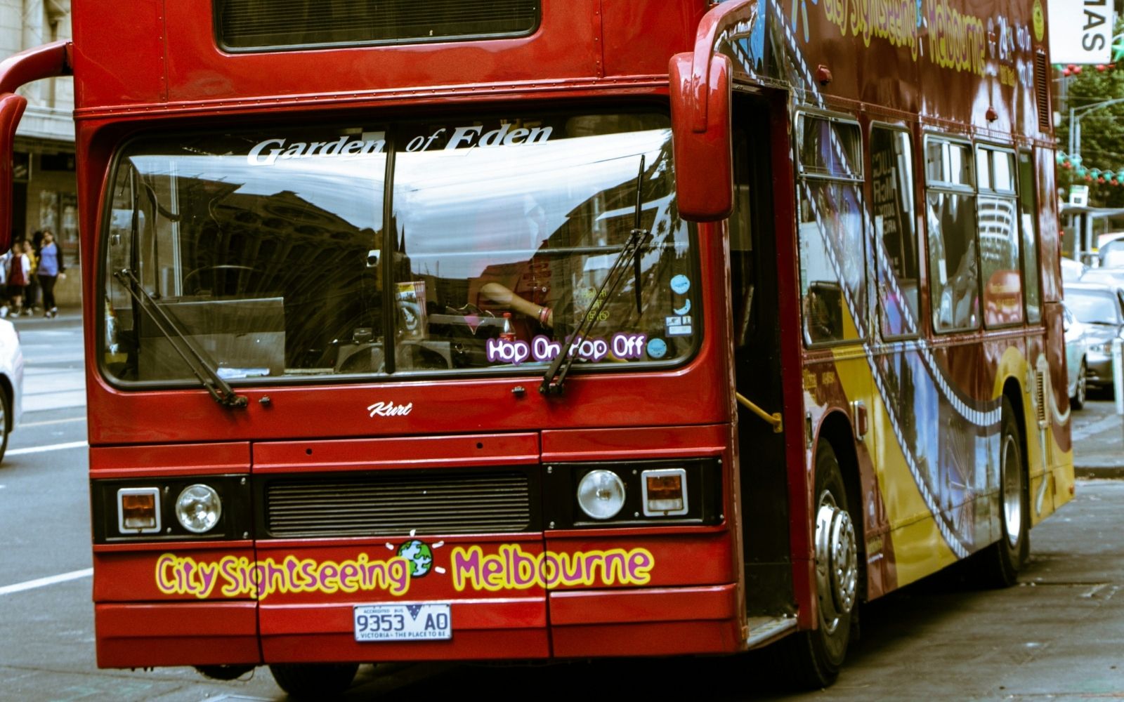Alt text: A red City Sightseeing Melbourne bus on a city street, with bus timetable upgrades set to boost services across Victoria