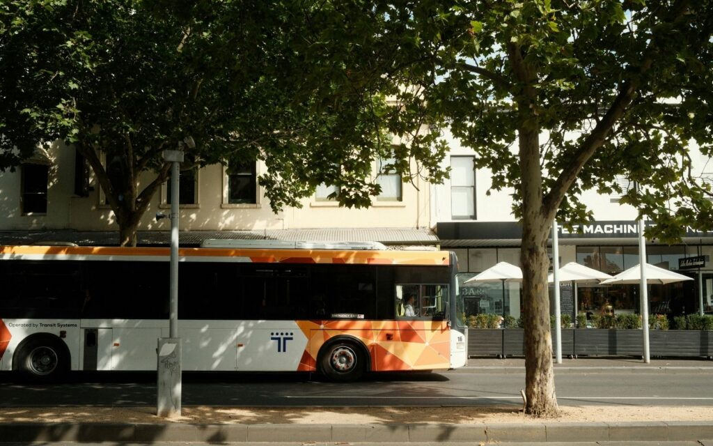 Alt text: A Transit Systems bus stopped on a tree-lined Melbourne suburban street, part of the network set to benefit from bus timetable changes