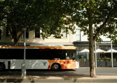 Alt text: A Transit Systems bus stopped on a tree-lined Melbourne suburban street, part of the network set to benefit from bus timetable changes