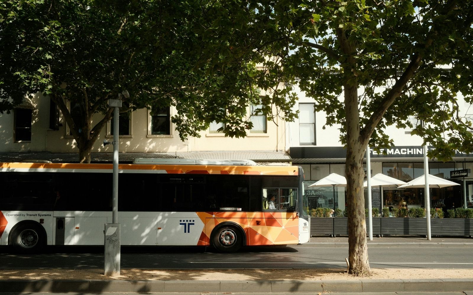 Alt text: A Transit Systems bus stopped on a tree-lined Melbourne suburban street, part of the network set to benefit from bus timetable changes