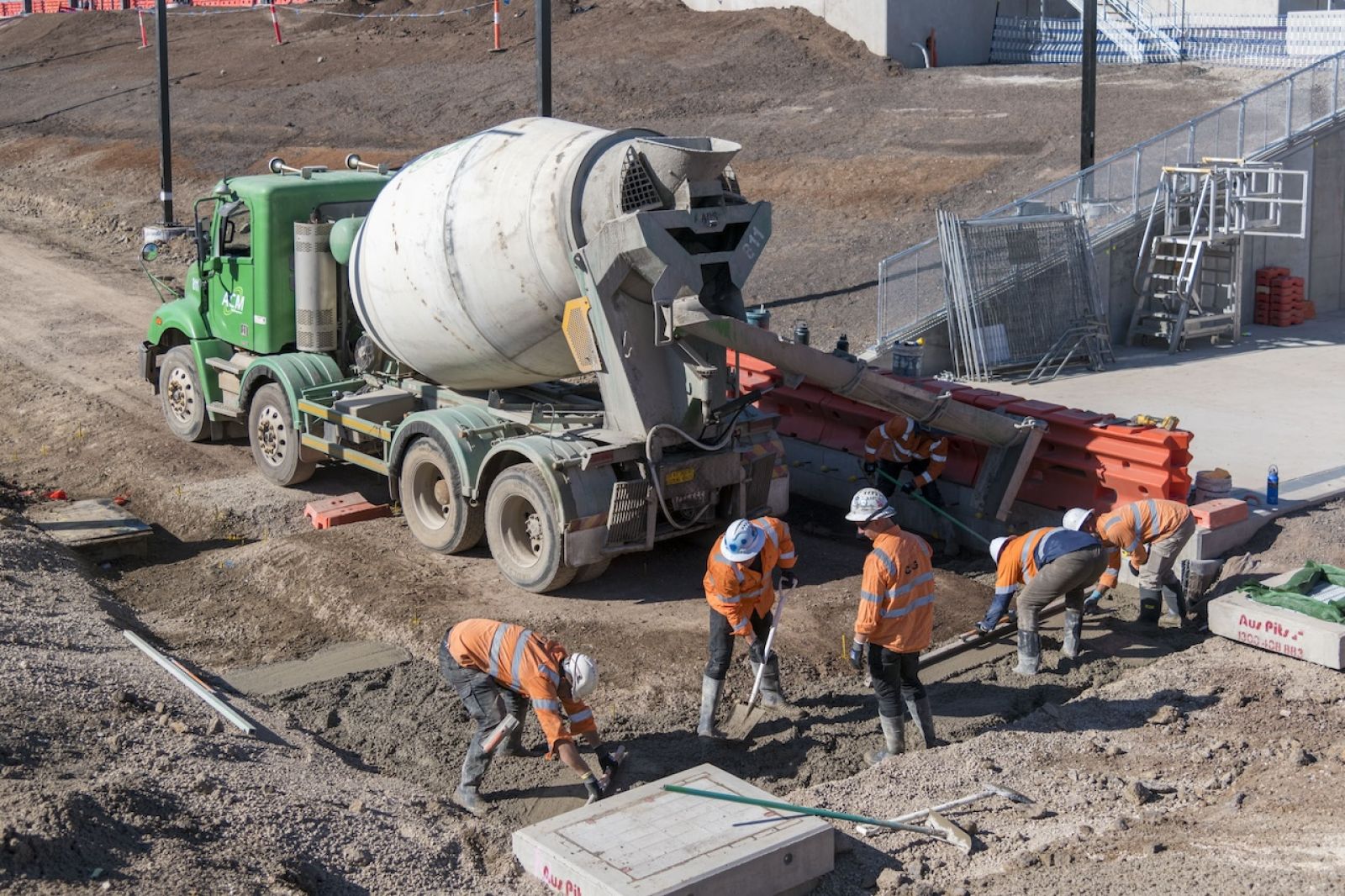 A worker guides concrete from a truck chute into a bucket at the new Melbourne train station site at West Tarneit.