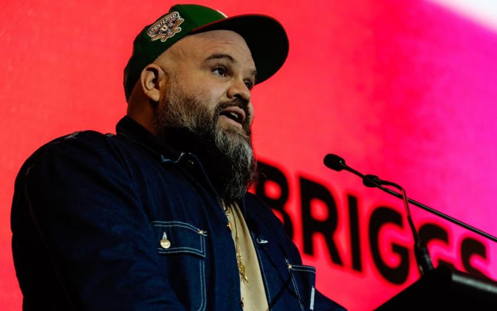 Briggs in front of a pink background, campaigning for greater music funding this Victorian election.